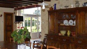 Un comedor con una mesa de madera, sillas, una planta en maceta y un mueble con vajilla.