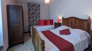A bedroom with two beds, a wardrobe, a patterned wall, and a ceiling light.
