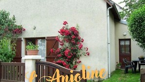 A house with a garden, a wooden gate, and a sign that reads "L'Ajoline".