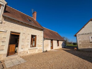 A stone building with a gravel driveway, a wooden door, and a chimney. - Spacious Cottage near Valençay Castle & Beauval Zoo with Outdoor Activities & Large Garden (Vicq-sur-Nahon)