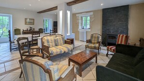 A spacious living room with a fireplace, wooden furniture, and a dining area with a table and chairs. - Charming Retreat in Berry: Heated Pool, Canoeing, Fishing, Near George Sand's House (Ardentes)