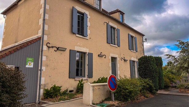 A two-story building with a no parking sign, a small garden, and a street lamp.