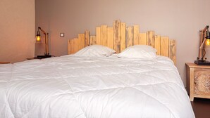 A bed with a wooden headboard, two bedside lamps, and a nightstand with a decorative item.