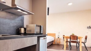 A compact kitchen with a microwave, kettle, and a built-in dishwasher.