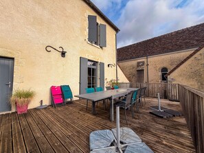 An outdoor patio with a wooden deck, a table with chairs, and a potted plant.