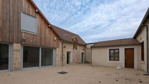 A building with a gravel courtyard, large windows, and a door. - Charming Ground-Floor Cottage in Brenne with Enclosed Courtyard, Near Fishing and Birdwatching Spots (Neuillay-les-Bois)