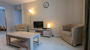 A living room with a TV, two chairs, a coffee table, and a lamp. - Charming Ground-Floor Cottage in Brenne with Enclosed Courtyard, Near Fishing and Birdwatching Spots (Neuillay-les-Bois)