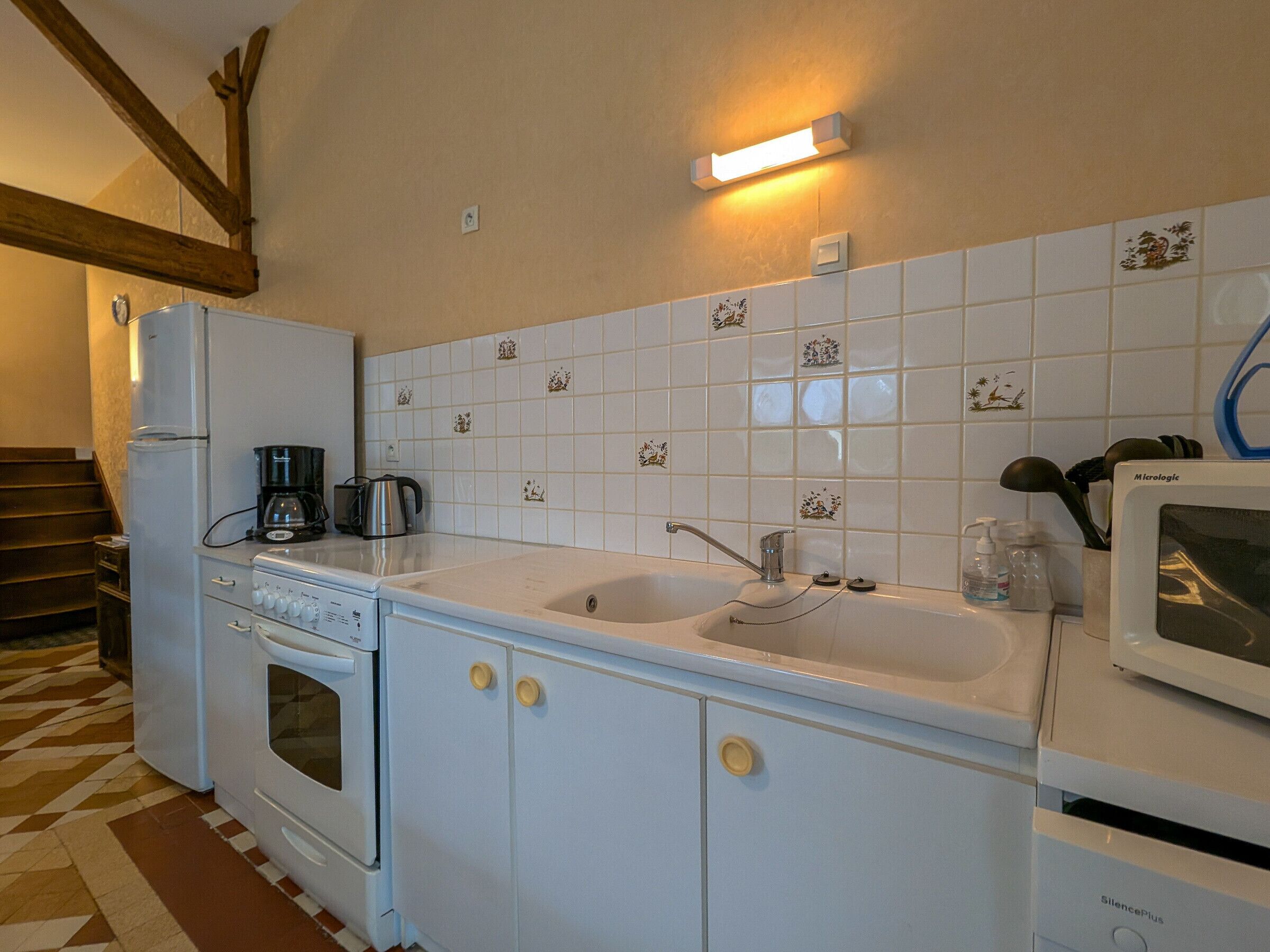A kitchen with white cabinets, a stove, a sink, and a microwave.