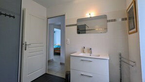 Een badkamer met een witte wastafel, spiegel en douche.