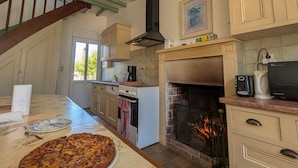 Een keuken met een open haard, houten balken en een eethoek met een grote taart.