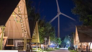 A campsite with tents, a wind turbine, and a paved path. - Nayang Beach (Taichung)