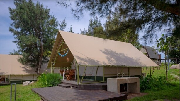 A tent-style accommodation with a stage, seating area, and a small outdoor kitchen. - Nayang Beach (Taichung)
