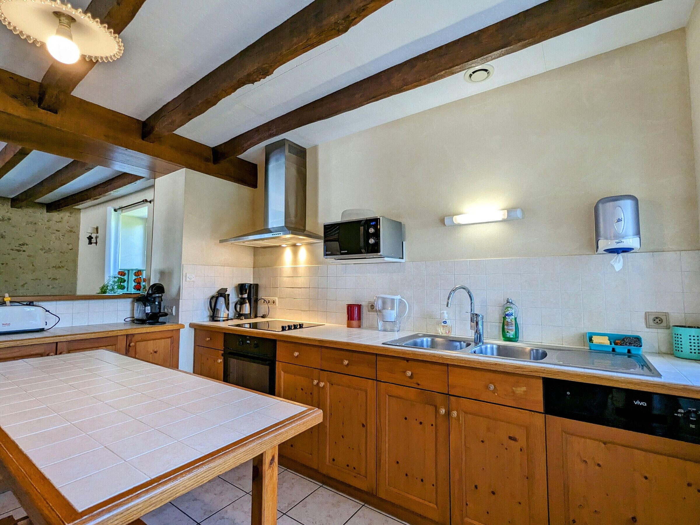 A kitchen with wooden cabinets, a microwave, a coffee maker, and a sink.