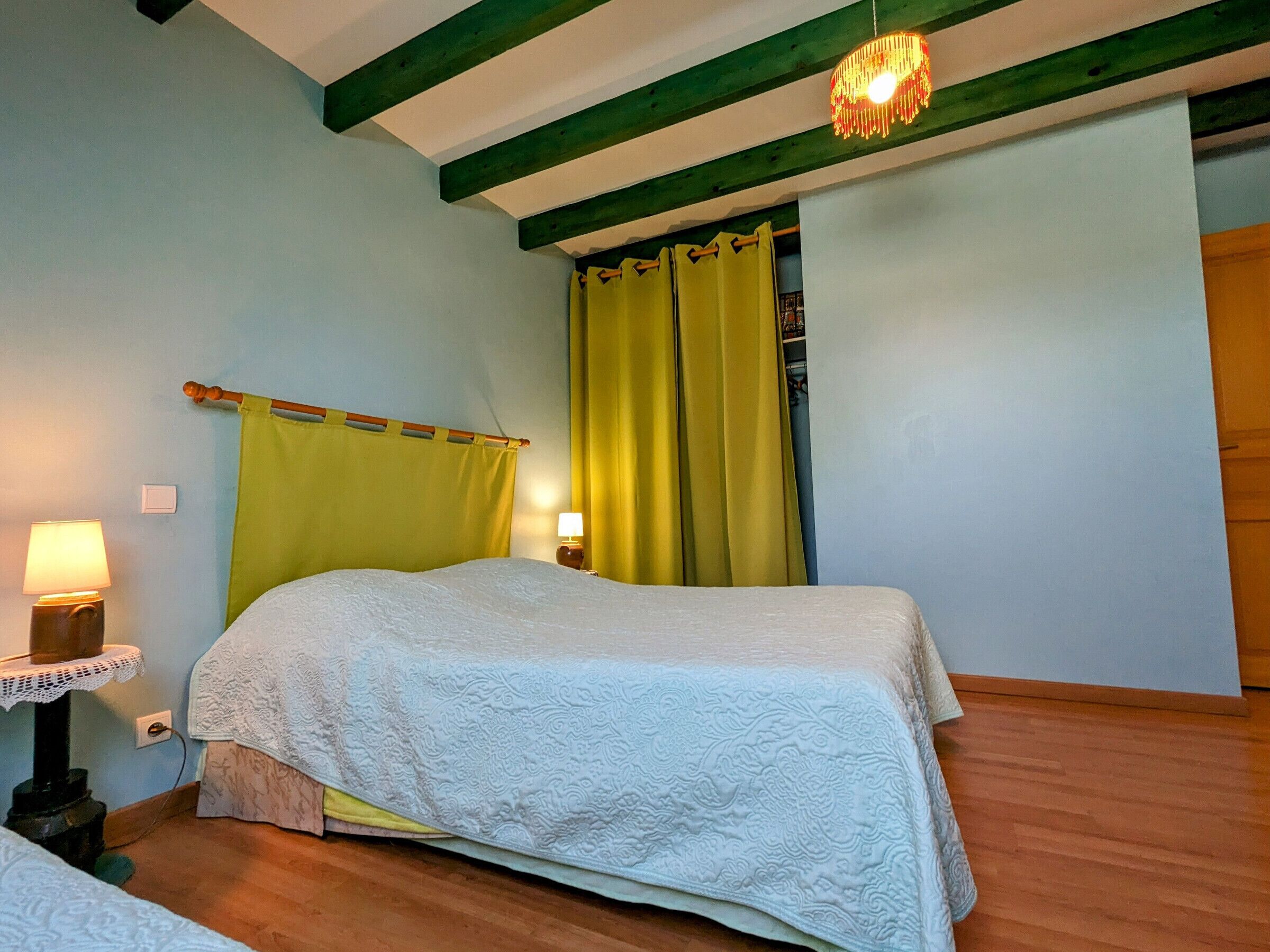 A bedroom with a bed, a nightstand, a lamp, and a window with curtains.