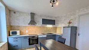 A compact kitchen with a microwave, oven, sink, and a dining table. - Charming Country Cottage Near Valençay - 2 Bedrooms, Quiet Garden, Close to Loire Castles & Beauval Zoo (Poulaines)
