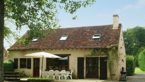 Een landelijke woning met pannendak, een overdekte patio met tuinmeubilair en een oprit met grind.