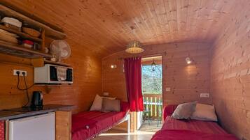 A cozy cabin with two beds, a kitchenette, and a small dining area.