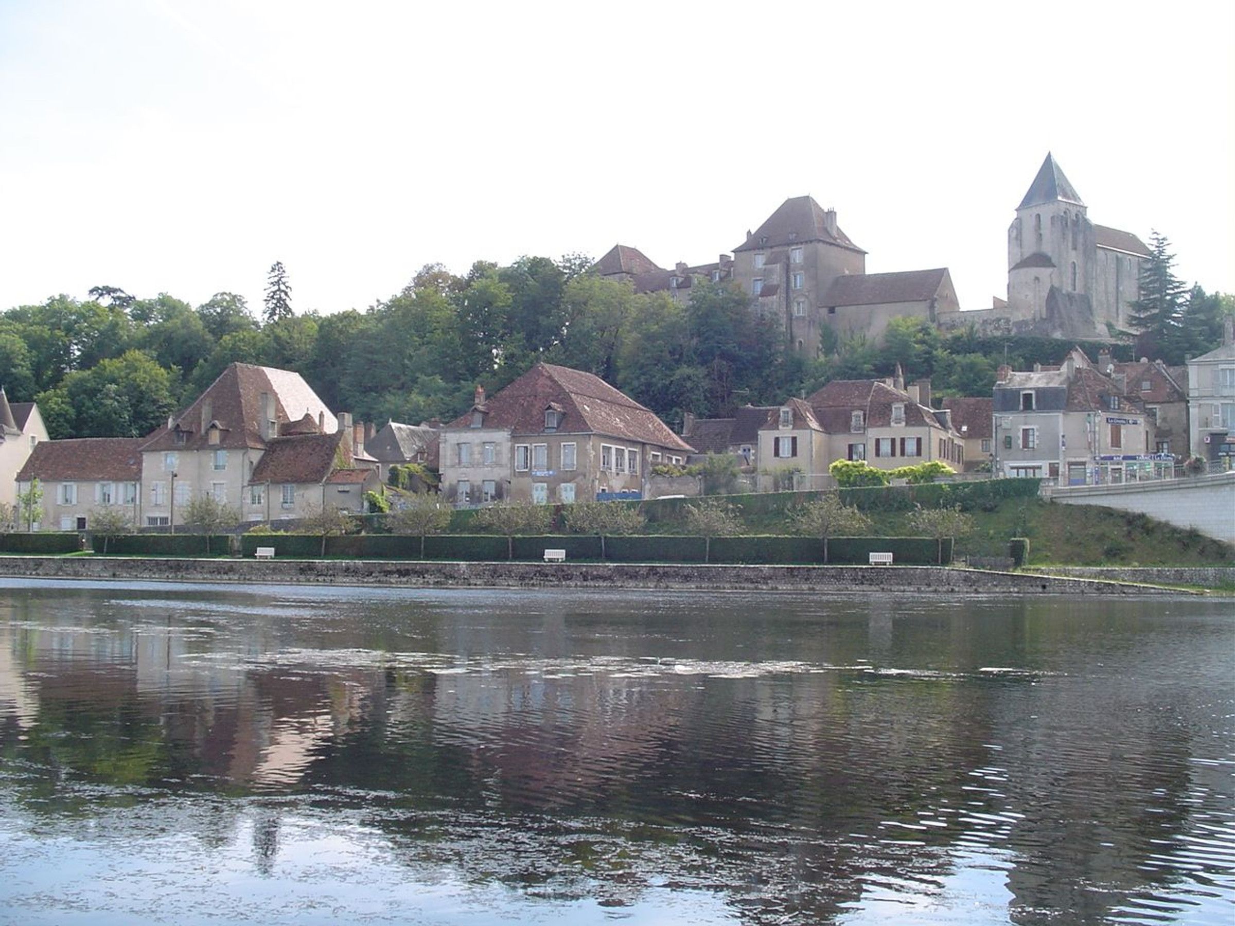 Une ville riveraine dotée de bâtiments historiques, parmi lesquels une église remarquable située sur une colline.
