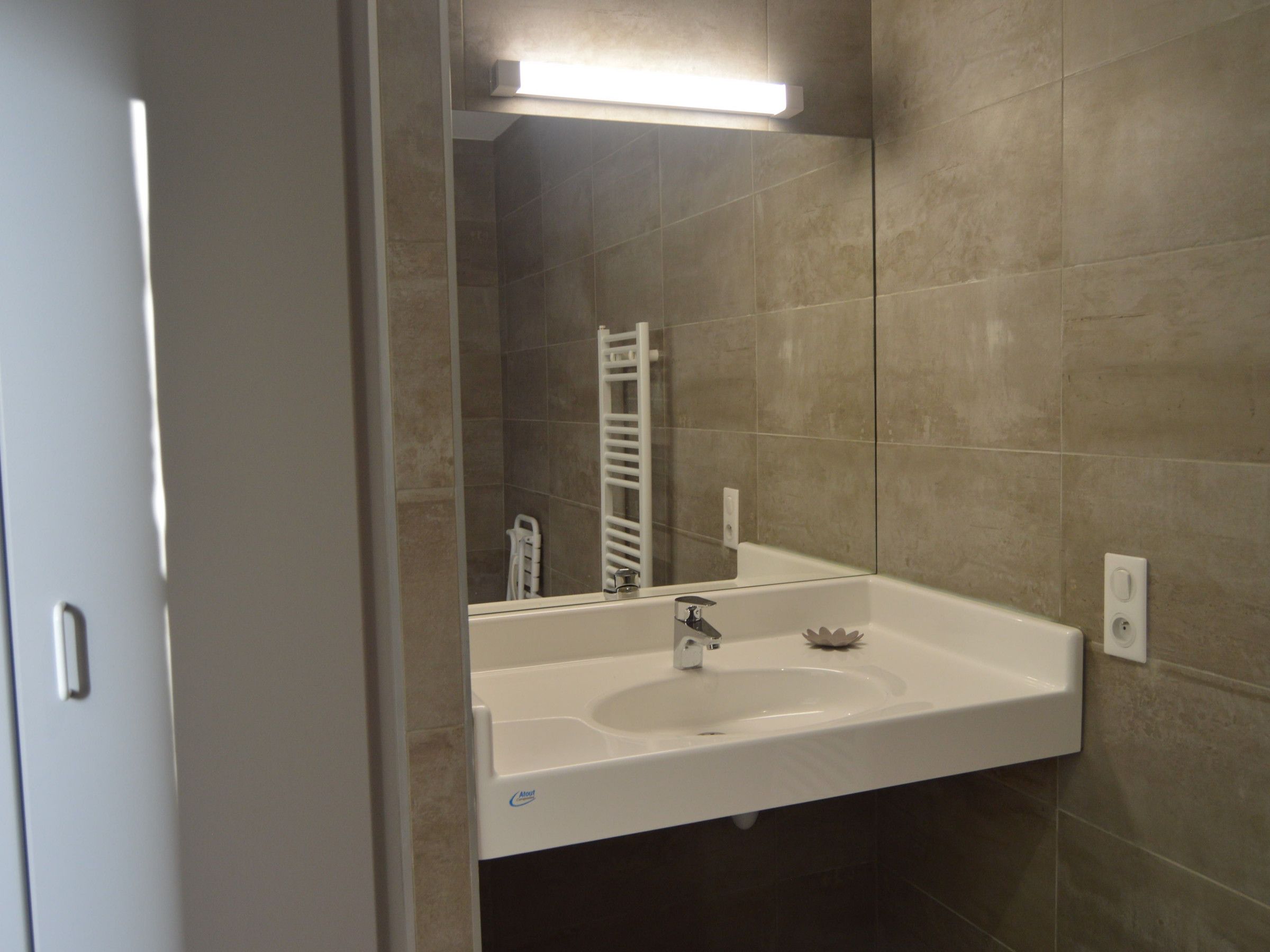 A bathroom with a white sink, a mirror, and a towel rack.