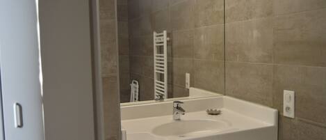 A bathroom with a white sink, a mirror, and a towel rack.