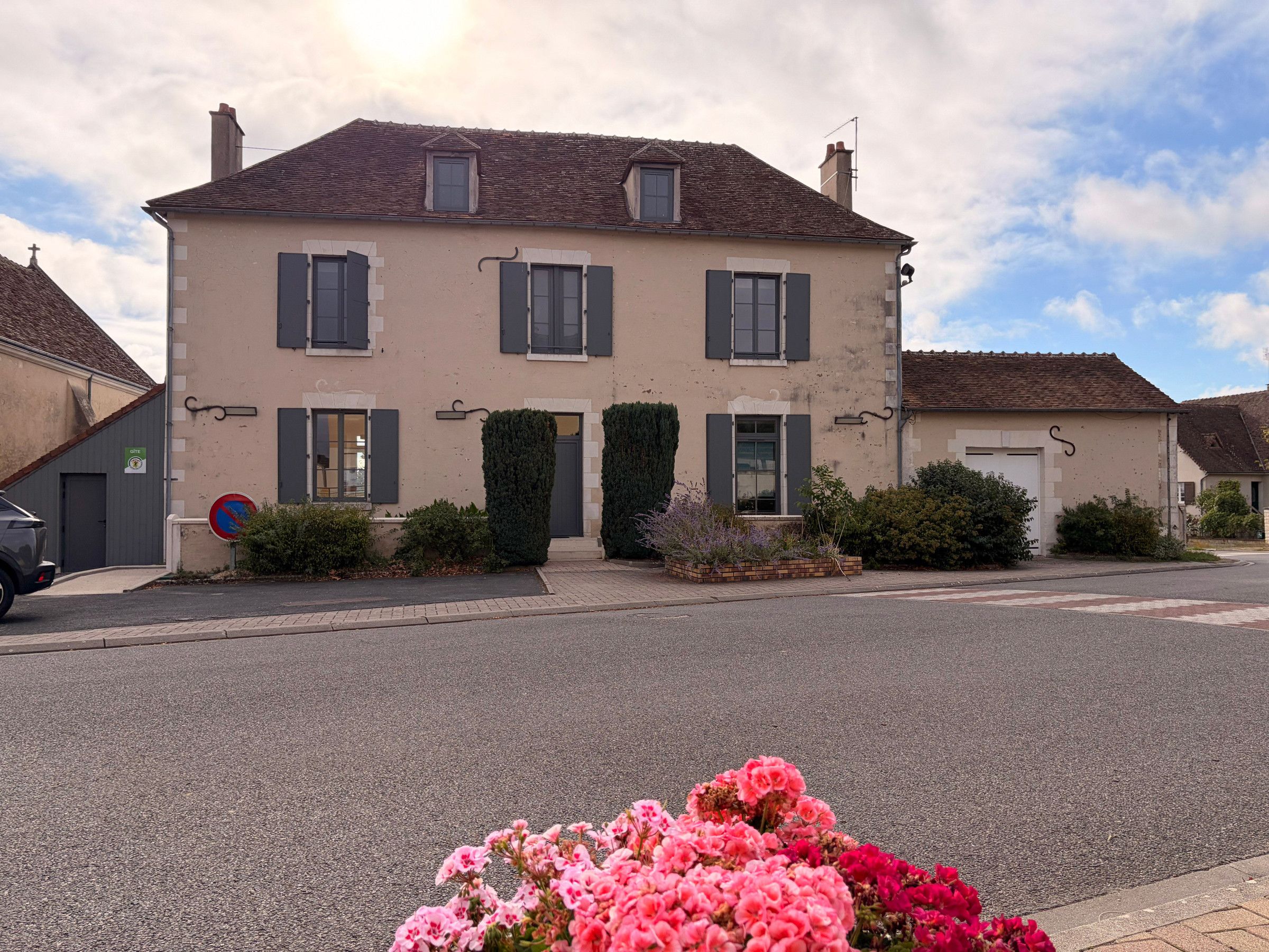 A two-story building with a symmetrical facade, a small front garden, and a clear sky.