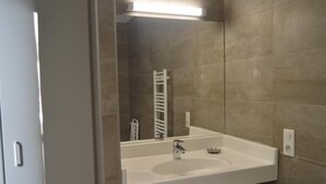 Ein Badezimmer mit einem weißen Waschbecken, einem Spiegel und einem Handtuchhalter.