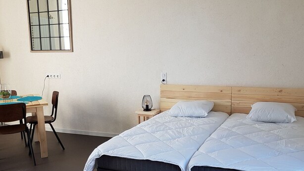 Ein Schlafzimmer mit zwei Betten, einem Schreibtisch und einem Stuhl.