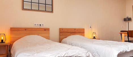 Une chambre d’hôtel avec deux lits, une table de chevet avec une lampe, une chaise et un miroir fixé au mur.