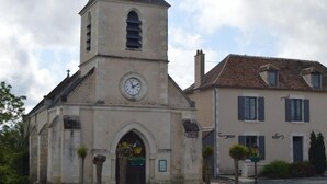 Eine Kirche mit einem Glockenturm und ein zweistöckiges Gebäude mit Fensterläden.