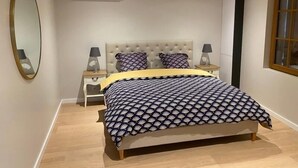 Un dormitorio con cama, dos mesitas de noche, un espejo, un equipo de aire acondicionado y una ventana.