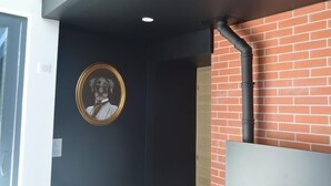 Una habitación con pared negra, un cuadro enmarcado, pared de ladrillo y una tubería negra.