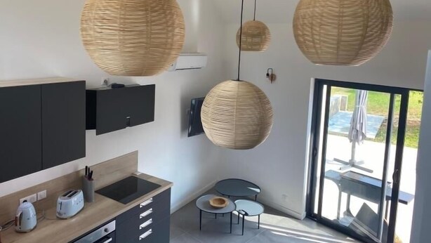 Una cocina moderna con encimera oscura, horno empotrado y un pequeño comedor con una mesa redonda y dos sillas.