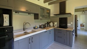 Una cocina moderna con armarios grises, un lavamanos de acero inoxidable y un horno empotrado.