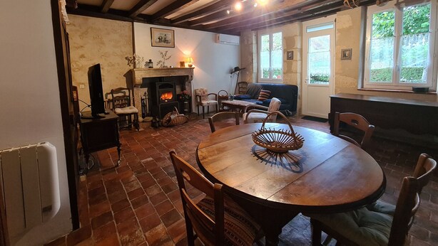 A cozy room with a fireplace, wooden furniture, and large windows.