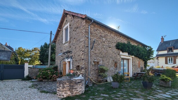 A stone house with a garden, a well, and a small pond.
