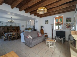 A living room with a sofa, a dining table, and a kitchen in the background.