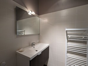 A modern bathroom with a white sink, dark cabinet, and a towel rack.