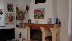 A living room with a fireplace, a television, and various decorative items.