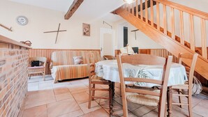 Une pièce chaleureuse avec un escalier en bois, une table à manger avec des chaises, un canapé et un mur en briques.