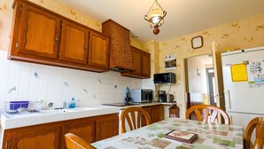 Eine Küche mit Holzausstattung, einer Mikrowelle, einem Kühlschrank und einem Esstisch mit Stühlen.