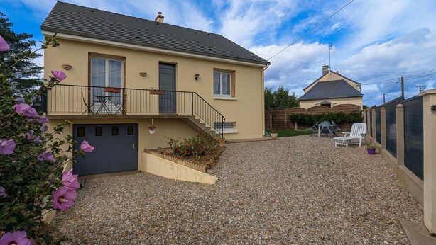 Ein zweistöckiges Haus mit Schotterauffahrt, einem Balkon mit Gartenmöbeln und einem durch Zäune umfriedeten Hinterhof.