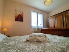 Une chambre à coucher avec un lit, une fenêtre, un radiateur, une lampe et une armoire en bois.