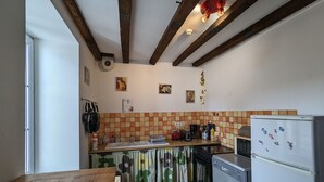 Eine kleine Küche mit Holztisch, Kühlschrank und gefliestem Spritzschutz.