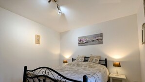A bedroom with a bed, two bedside tables, a ceiling light fixture, and a wall-mounted picture. - Family-Friendly Cottage in Brenne Park with Bikes, BBQ & Near Lake! (Luant)