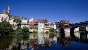A historic town with a stone bridge over a calm river, reflecting the buildings and the clear blue sky. - Family-Friendly Cottage in Brenne Park with Bikes, BBQ & Near Lake! (Luant)