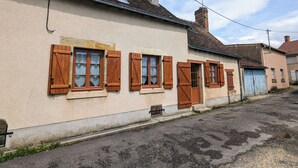 A row of houses with wooden shutters, a visible chimney, and a clear sky.