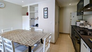 A compact kitchen with a dining table, chairs, and modern appliances.