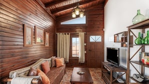 A wooden interior with a sofa, television, and shelves.
