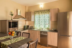 Eine moderne Küche mit Mikrowelle, Backofen und Geschirrspüler, einem Esstisch mit Stühlen und einem Fenster mit Blumenvorhang.