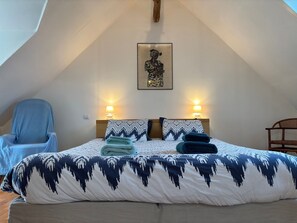 Een slaapkamer met een bed, twee nachtkastjes, een stoel en een houten bank.